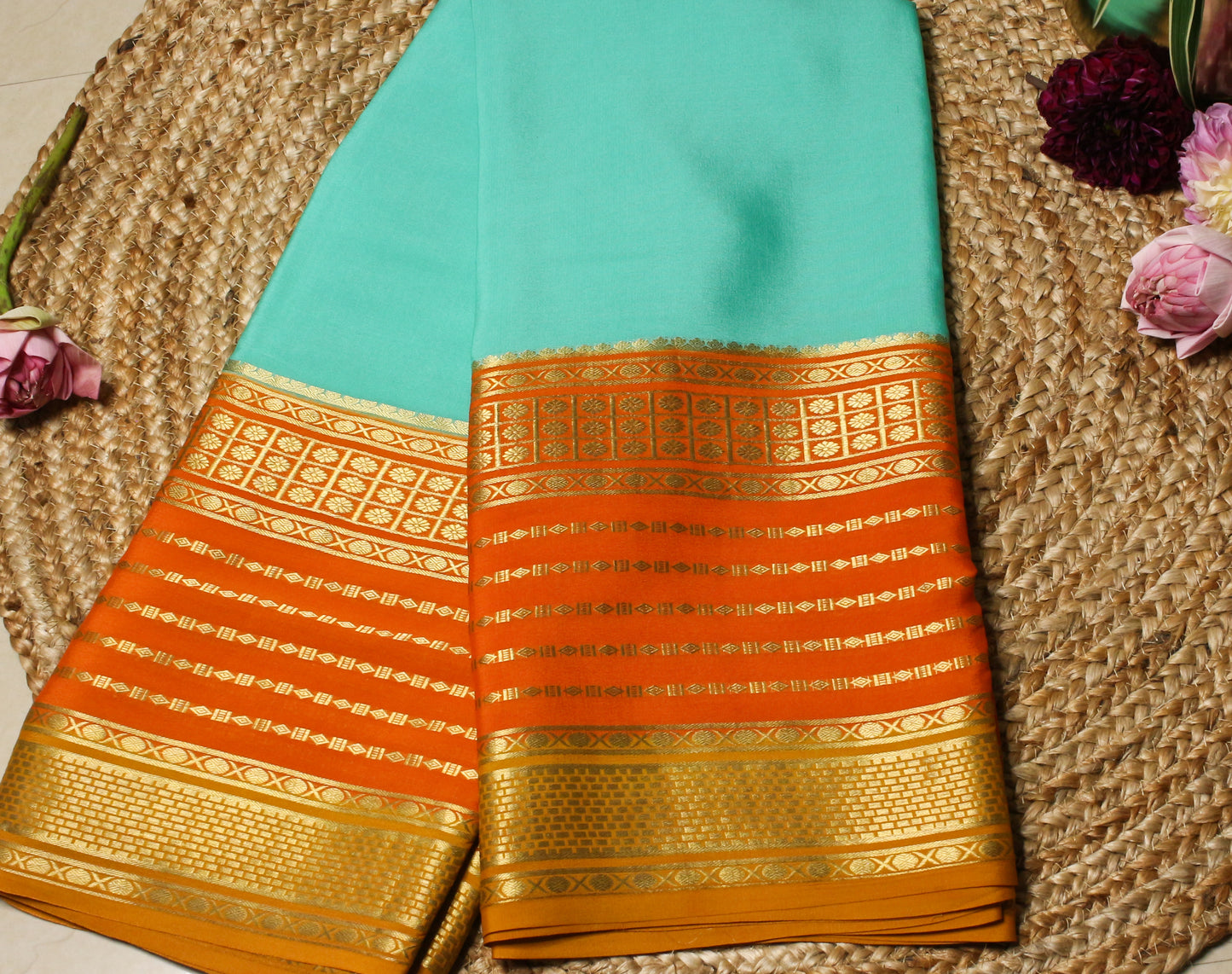Traditional saree with gold and orange patterns on a textured surface