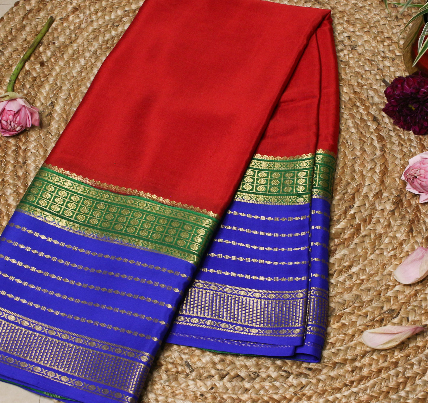 Red and blue saree with green border on a textured surface