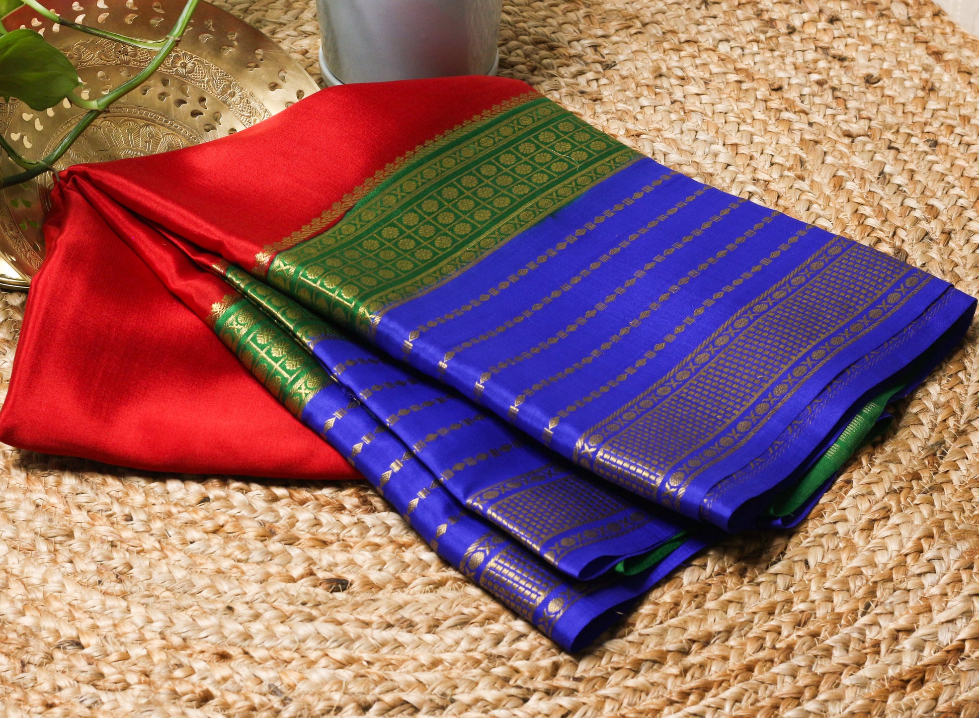 Red and blue sarees with green border on a woven surface