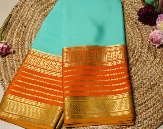 Traditional saree with gold and orange patterns on a textured surface