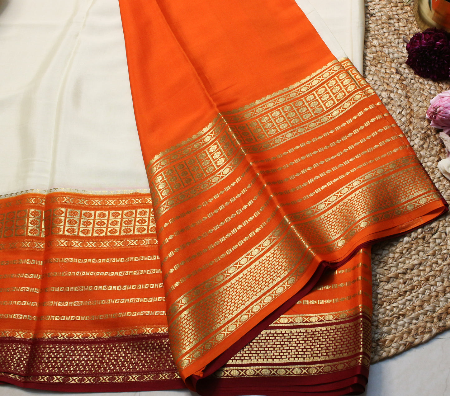 Orange saree with gold patterns on a textured surface