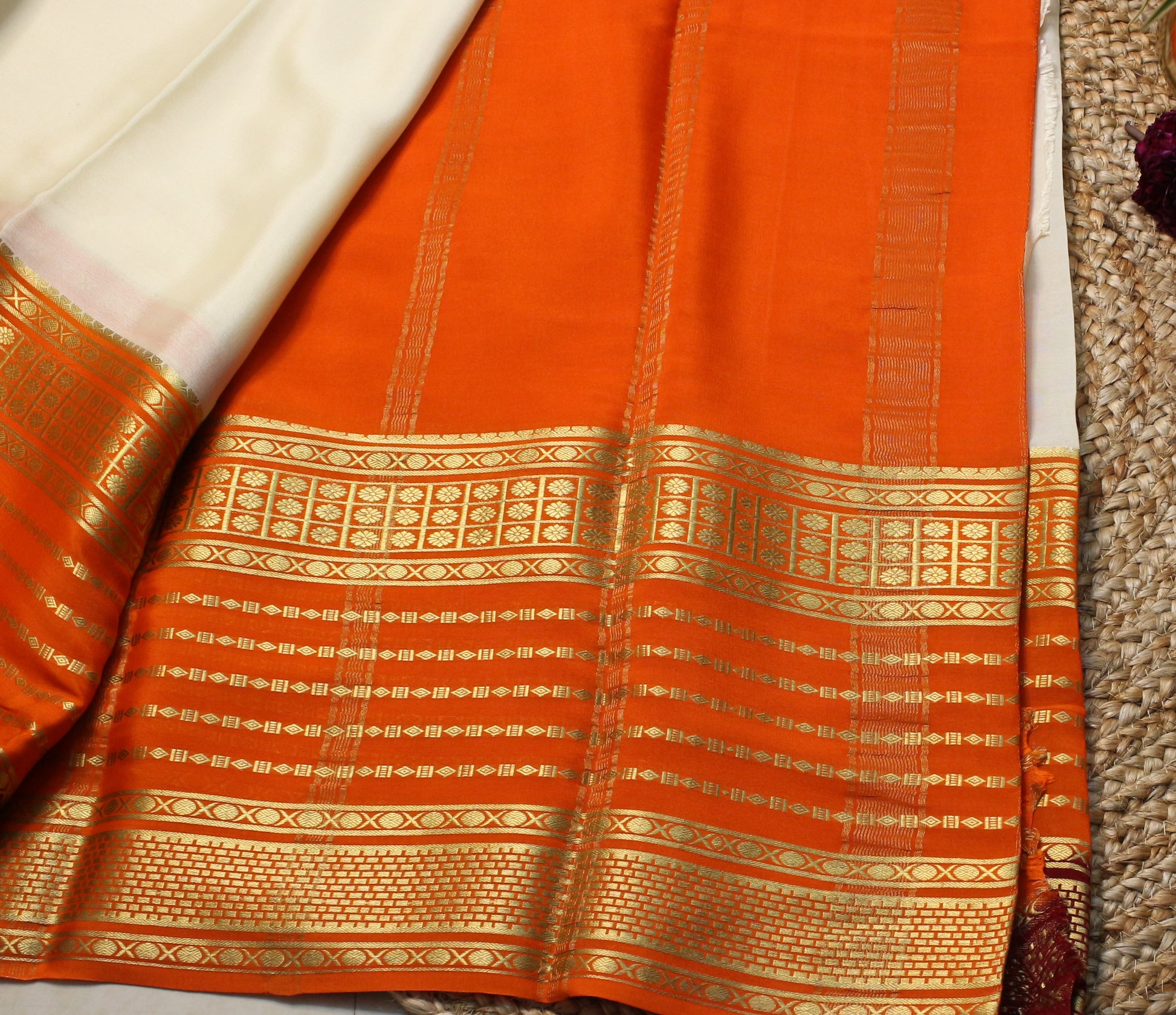 Orange saree with gold patterns on a textured surface
